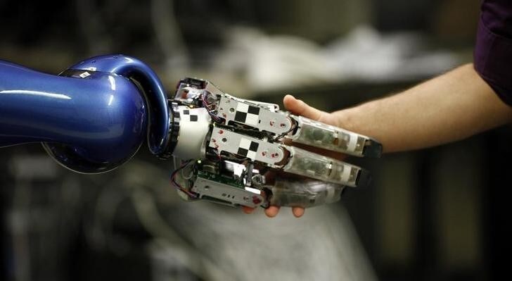 Alexander Dietrich of the German air and space agency, Deutsches Zentrum fuer Luft und Raumfahrt (DLR), shakes the hand of the humanoid two arm system robot Justin during a presentation in Oberpfaffenhofen near Munich June 1, 2011. The mobile robotic system Justin with its compliant controlled light weight arms and its two four finger hands allows the long range autonomous operation of the system. Sensors and cameras allow the 3D reconstruction of the robot's environment and therefore enable Justin to perform given tasks autonomously such as catching balls or serving coffee. REUTERS/Michael Dalder(GERMANY - Tags: SOCIETY SCI TECH)
