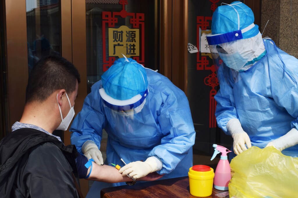 A worker from the city's center for disease control and prevention draws blood from a man to conduct a test for antibodies against the coronavirus disease (COVID-19) in Suifenhe, a city bordering Russia in China's Heilongjiang province, April 16, 2020. REUTERS/Huizhong Wu - RC2I5G9AFICT