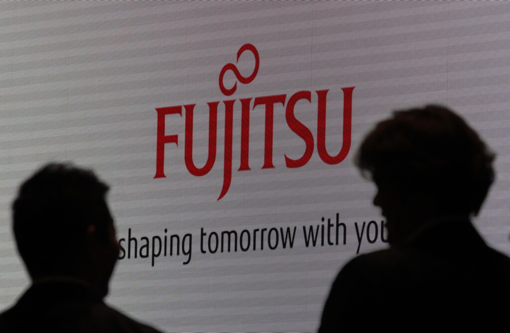 People are silhouetted against a screen displaying a logo of Fujitsu at CEATEC JAPAN 2012 electronics show in Chiba, east of Tokyo, October 2, 2012. Japan's largest cutting-edge IT and electronics trade show started on Tuesday and runs until October 6 at Makuhari Messe convention center. REUTERS/Yuriko Nakao (JAPAN - Tags: BUSINESS) - GM1E8A21I2401