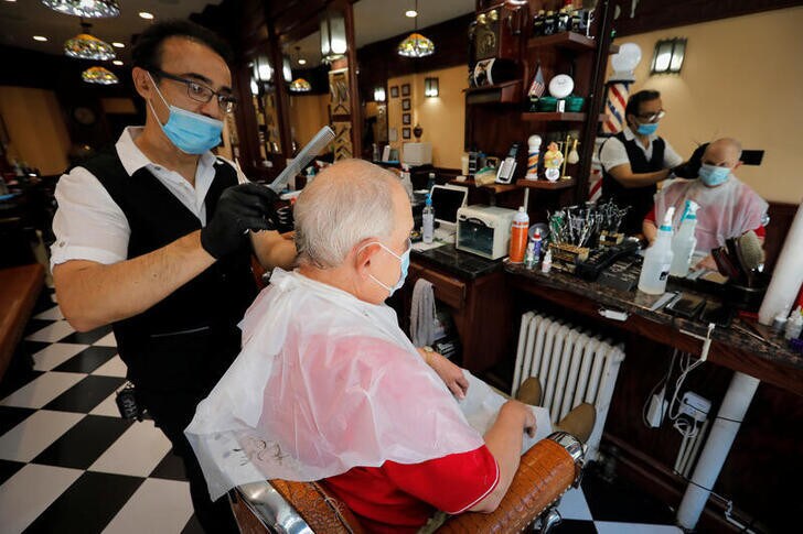 Igor Khaimov gives a customer a haircut at the Little Tony & Igor Be Good Barber Shop in Manhattan, on the first day of the phase two re-opening of businesses following the outbreak of the coronavirus disease (COVID-19), in New York City, New York, U.S., June 22, 2020. REUTERS/Mike Segar