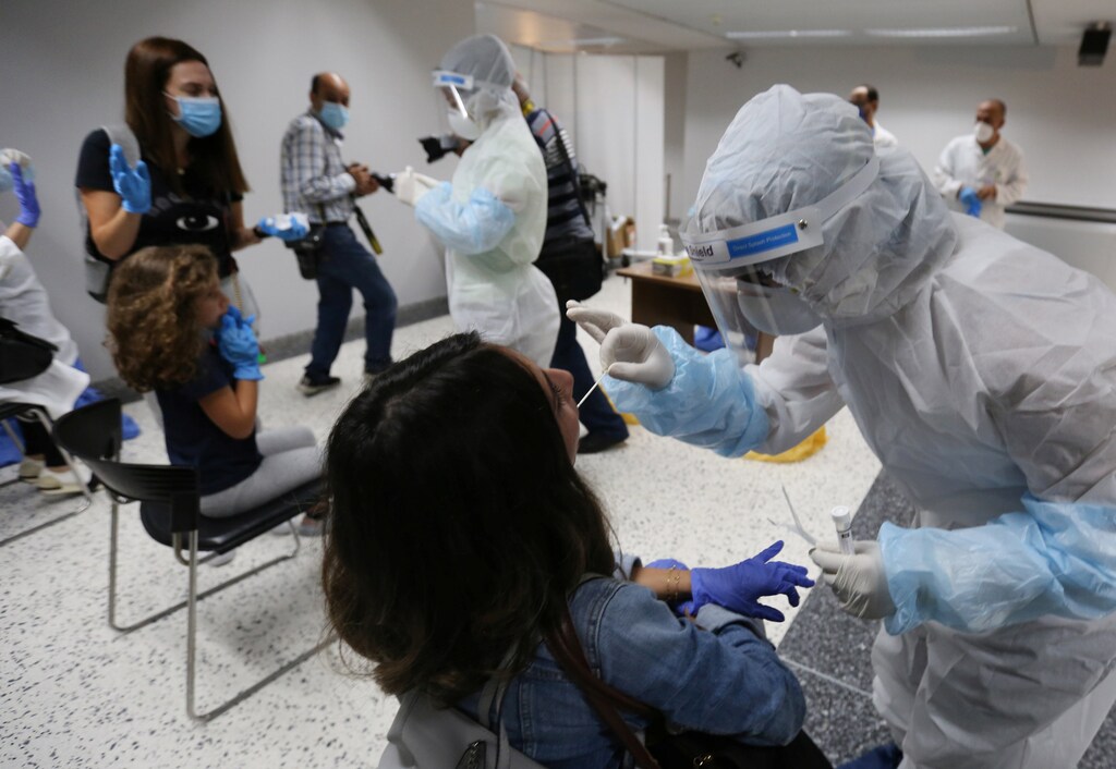 Trabajadores sanitarios toman muestras de hisopos de los pasajeros que llegaron al aeropuerto internacional de Beirut en su día de reapertura tras el brote de la enfermedad coronavirus (COVID-19), en Beirut, Líbano, el 1 de julio de 2020