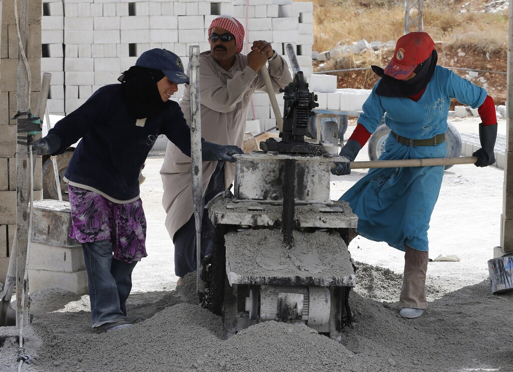 Syrian refugees work to help produce concrete blocks in Bekaa Valley, Lebanon.