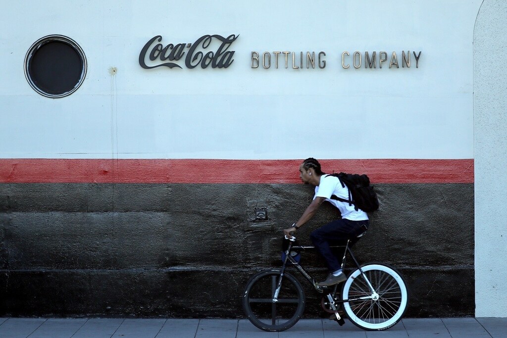 A man cycles past the Coca Cola bottling plant in Los Angeles, California, U.S. October 24, 2017. REUTERS/Lucy Nicholson - RC18A6259170