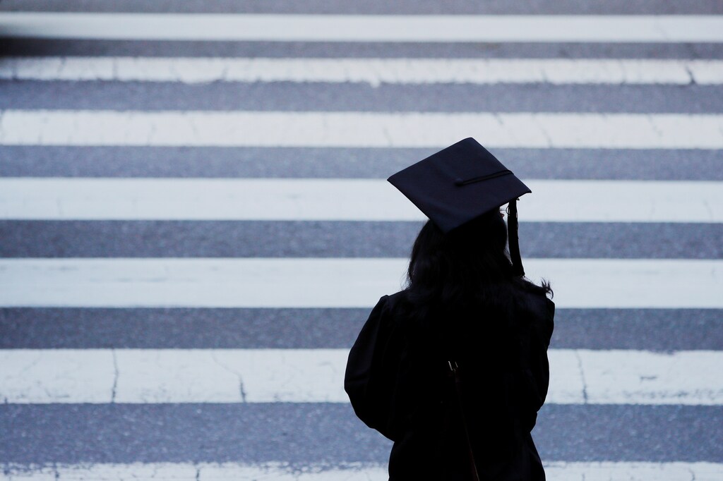 A graduating student waits to cross the street before Commencement Exercises at the Massachusetts Institute of Technology (MIT) in Cambridge, Massachusetts, U.S., June 7, 2019. REUTERS/Brian Snyder - RC15B2D28AF0