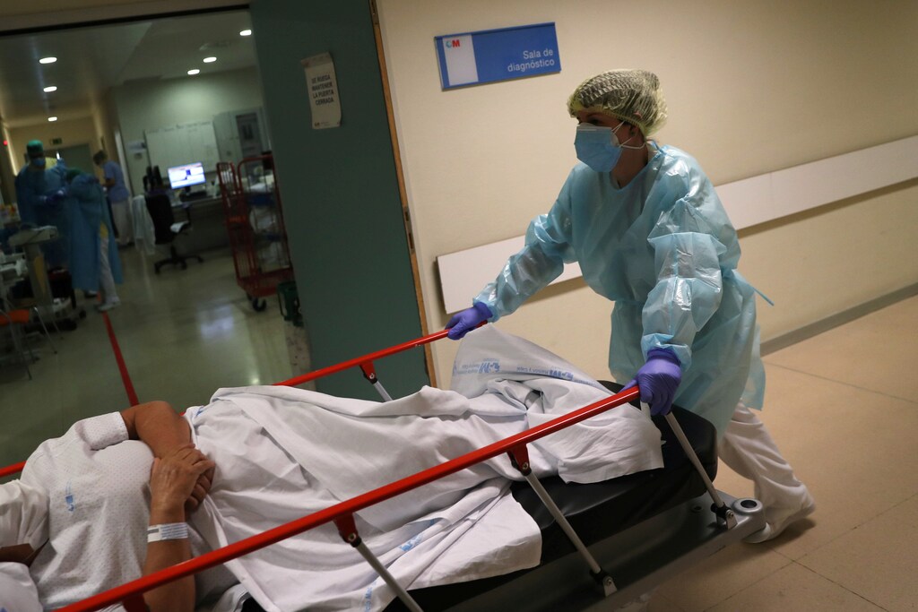 A healthcare workers in protective gear pushes a patient past the emergency room as the spread of the coronavirus disease (COVID-19) continues, at Infanta Sofia University hospital in Madrid, Spain, May 8, 2020. REUTERS/Susana Vera - RC2CKG91S07J