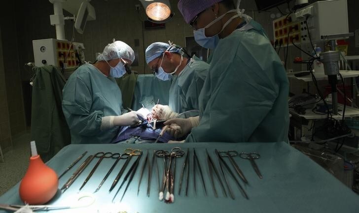Professor Jan Pirk (L), doctor Marian Urban and suture nurse Diana Vapenkova (R) perform a heart surgery at the Institute of Clinical and Experimental Medicine (IKEM) in Prague, June 28, 2012. A Czech medical team led by Pirk has performed a breakthrough operation on a 37-year-old heart failure patient, replacing his heart with two mechanical blood pumps, HeartMate II. The man is the first to survive such surgery, which was performed on April 3. The exact operation was previously conducted by heart surgeons in Texas, United States. However, the patient died one week later. Picture taken on June 28, 2012. REUTERS/Petr Josek (CZECH REPUBLIC - Tags: HEALTH SCIENCE TECHNOLOGY SOCIETY)