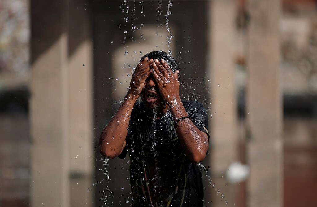 A man bathes under a broken water pipeline next to a drain on a hot summer day in New Delhi, India June 5, 2017. REUTERS/Adnan Abidi - RTX394M5
