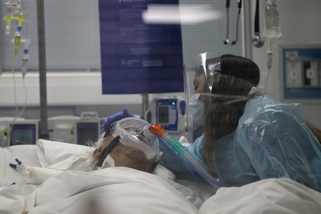 A relative touches 76-year-old Don Jaime, who is infected with the coronavirus disease (COVID-19), during a final goodbye inside an Intensive Care Unit of the University of Chile's clinical hospital in Santiago, Chile June 18, 2020. Picture taken June 18, 2020. REUTERS/Ivan Alvarado - RC21FH9QRUQJ