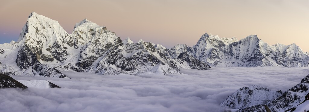 Los delicados cielos rosados del atardecer sobre las cumbres nevadas de Cholatse (6440 m), Taboche (6542 m), Kangtega (6752 m) y Thamserku (6623 m) se elevan a través de las nubes que cubren el glaciar Ngozumpa y Gokyo en lo profundo de la gran altitud del desierto montañoso del Himalaya del Everest National. Parque en la frontera entre Nepal y el Tíbet, declarado Patrimonio de la Humanidad por la UNESCO. Perfil ProPhoto RGB para máxima fidelidad y gama de colores. Tercer polo