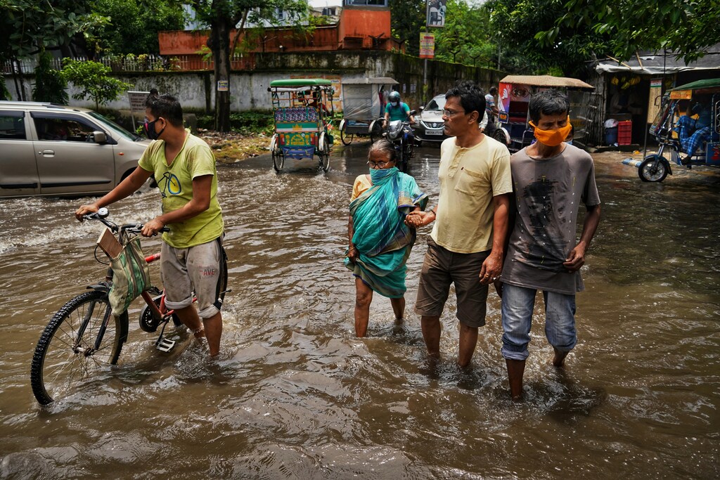 Un grupo de personas cruza una calle inundada, representando la necesidad de financiación para la adaptación al cambio climático.