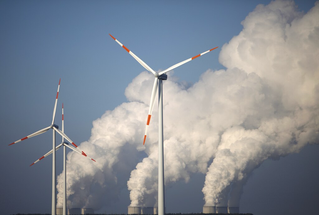 Steam billows from the cooling towers of Vattenfall's Jaenschwalde brown coal power station behind wind turbines near Cottbus, eastern Germany December 2, 2009. Most world leaders plan to attend a climate summit in Copenhagen December 7-18, boosting chances that a new U.N. deal to fight climate change will be reached, host Denmark said on Tuesday. REUTERS/Pawel Kopczynski (GERMANY - Tags: ENERGY ENVIRONMENT) - BM2E5C21BNF01