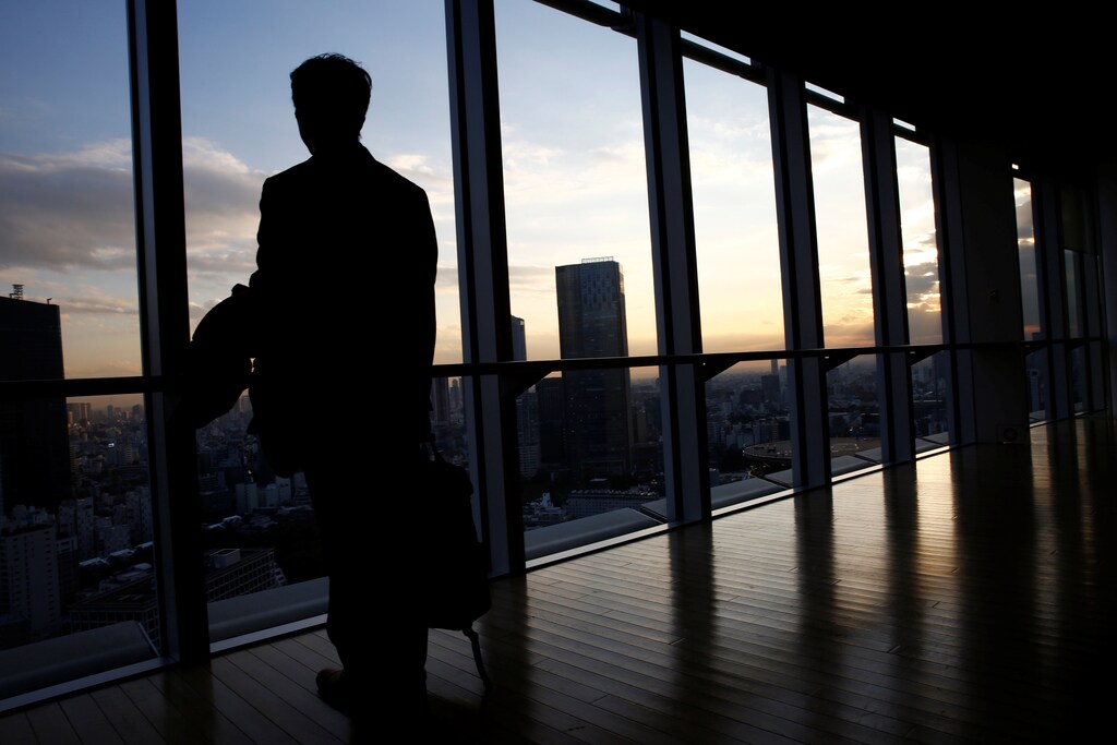 An IT engineer, who does not want to be identified, poses against a window where Tokyo's office buildings are seen after having an interview with Reuters in Tokyo, Japan, December 7, 2016. Picture taken on December 7, 2016. REUTERS/Kim Kyung-Hoon - RTX2VHOW