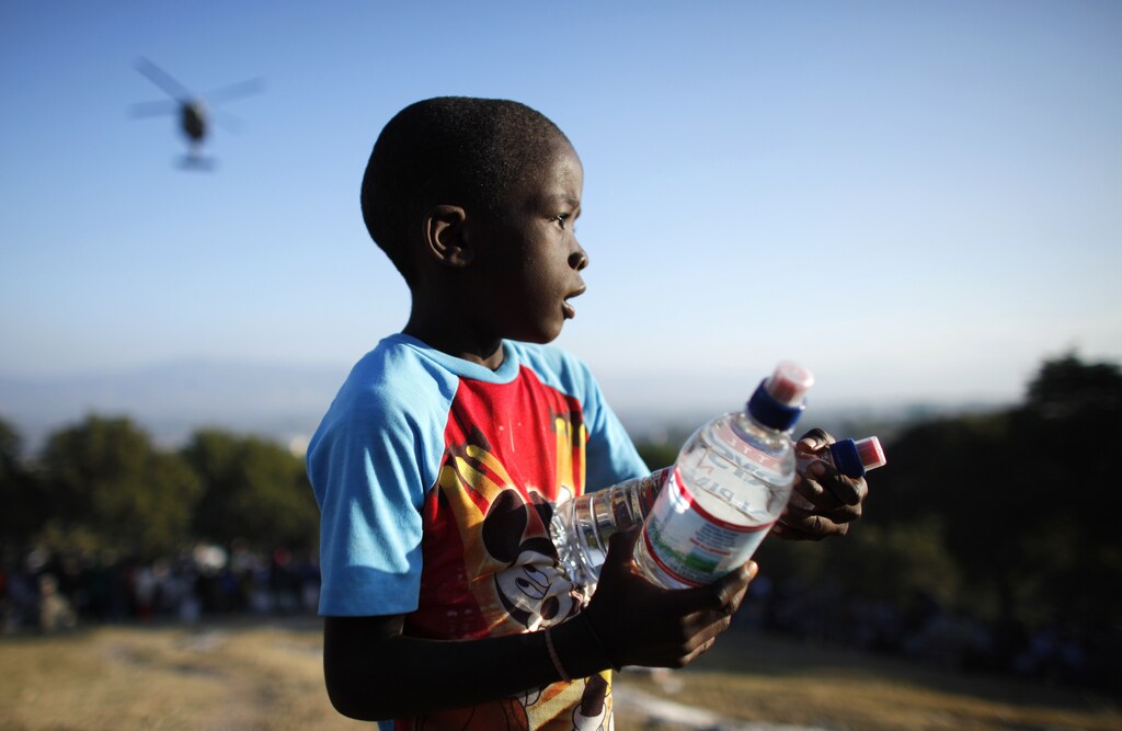 A Haitian boy receives water from U.S. forces at a food distribution point in Port-au-Prince January 19, 2010. Thousands more U.S. troops will help U.N. peace keepers keep order on Haiti's increasingly lawless streets as tens of thousands of survivors wait desperately for aid. REUTERS/Jorge Silva (HAITI - Tags: DISASTER ENVIRONMENT IMAGES OF THE DAY) - GM1E61K03ZQ01