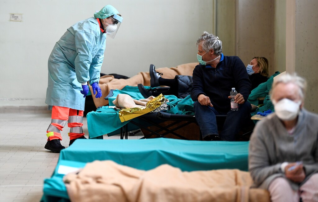 Medical personnel wearing protective face masks help patients inside the Spedali Civili hospital in Brescia, Italy March 13, 2020. REUTERS/Flavio Lo Scalzo - RC21JF9MW9JA