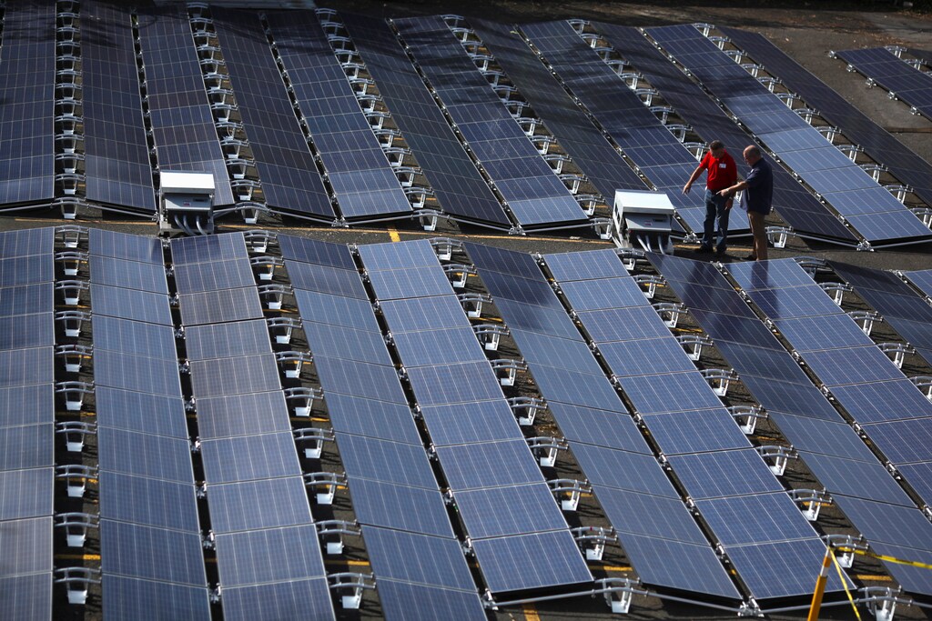 Men gesture next to solar panels set up by Tesla, at the San Juan Children's Hospital, after the island was hit by Hurricane Maria in September, in San Juan, Puerto Rico October 26, 2017. REUTERS/Alvin Baez - RC170359F4E0