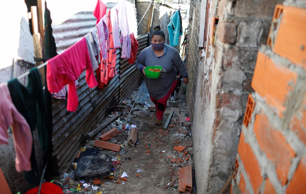 Silvia Puntano walks to her home after receiving a ration of stew in a plastic container at a soup kitchen, during the coronavirus disease (COVID-19) outbreak, in Villa Azul, on the outskirts of Buenos Aires, Argentina July 29, 2020. Picture taken July 29, 2020. REUTERS/Agustin Marcarian - RC2N7I9PV7QI