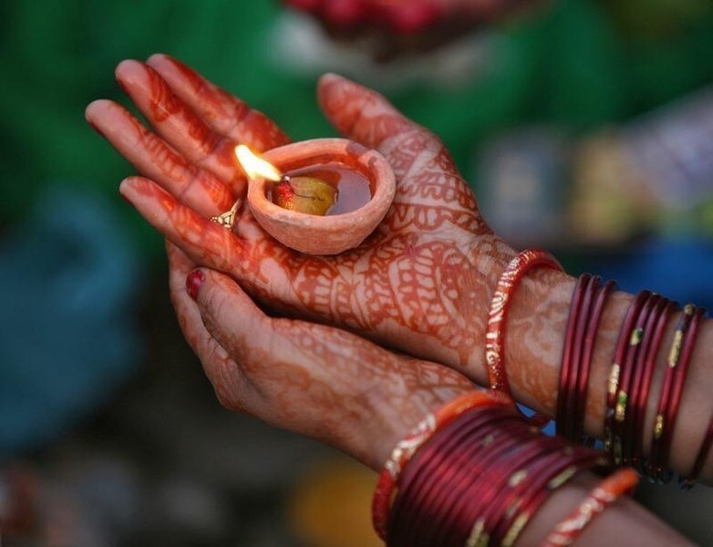 A Hindu woman devotee with her hands decorated with henna paste holds an earthen oil lamp while worshipping the Sun god during the Hindu religious festival "Chhat Puja" in Jammu November 1, 2011. Hindu devotees worship the Sun god and fast all day for the betterment of their family and society during the festival.
