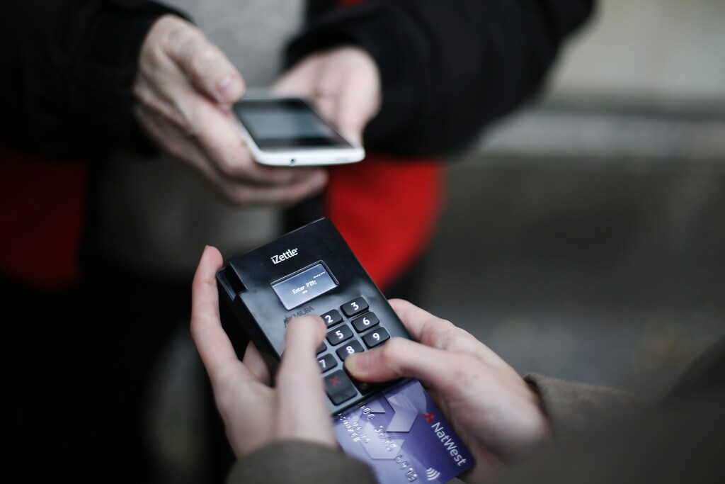 Big Issue vendor Simon Mott demonstrates using his Chip and Pin device outside South Kensington Tube Station in London November 28, 2013. Mott, who sells the Big Issue, a magazine which supports the homeless, has become the first of its vendors to start accepting card payments for the 2.50-pound publication. In an increasingly cashless society, Mott realised that he was losing customers who found themselves without any change, so in May he invested in a card payment system. REUTERS/Stefan Wermuth (BRITAIN - Tags: BUSINESS SOCIETY) - RTX15X3J
