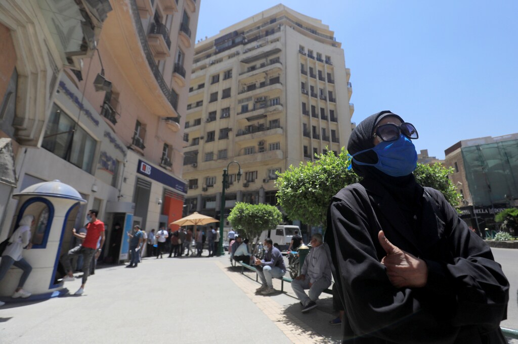 A woman wearing a protective mask looks on as people wait to make withdrawals outside a branch of Commercial International Bank (CIB), amid concerns over the coronavirus disease (COVID-19) in Cairo, Egypt May 31, 2020. Picture taken May 31, 2020. REUTERS/Amr Abdallah Dalsh - RC2D0H95JMAW