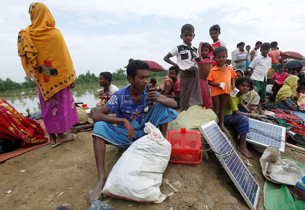 A Rohingya refugee charges his phone with a solar panel as he waits to be taken to a refugee camp after crossing the Naf river at the Bangladesh-Myanmar border in Palang Khali, near Coxs Bazar, Bangladesh November 2, 2017. REUTERS/Adnan Abidi - RC1143167130