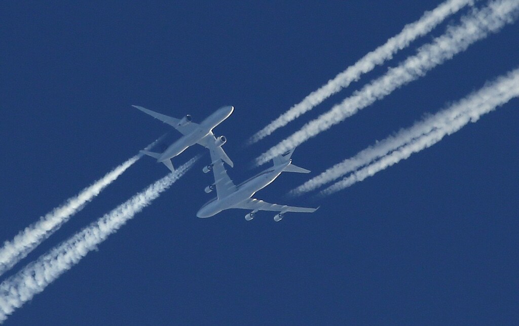 Two airline planes pass each other in the sky going opposite directions