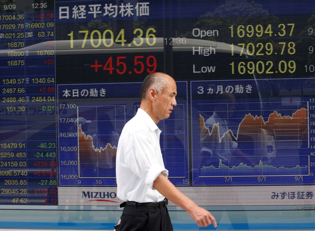 A man walks past a stock quotation board outside a brokerage in Tokyo, Japan.