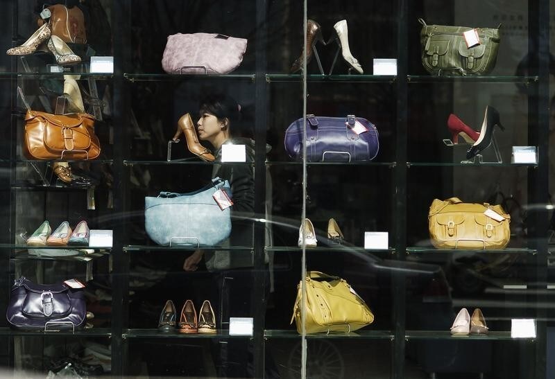 A woman passes by a shop window in Jinan, east China's Shandong province, March 9, 2007. A rapid expansion in China's retail sector and increased foreign participation in the domestic industry will herald a growing number of cases in merger and acquisitions, local media reported. CHINA OUT REUTERS/Stringer (CHINA) - RTR1N9PC