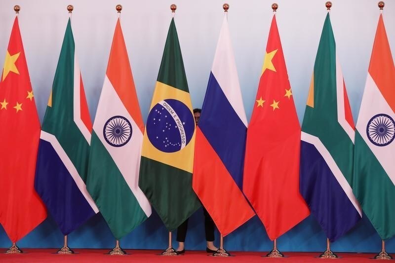 A staff worker stands behind the national flags of Brazil, Russia, China, South Africa and India to tidy the flags before a group photo during the BRICS Summit at the Xiamen International Conference and Exhibition Center in Xiamen, southeastern China's Fujian Province, China September 4, 2017. REUTERS/Wu Hong/Pool - RC1BBBFA1AD0