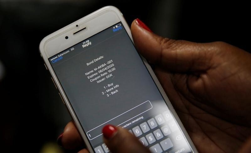 A delegate uses her cell phone to buy a M-Akiba bond during the launch of the first mobile-phone-based government bond at the Treasury building in Nairobi, Kenya March 23, 2017. REUTERS/Thomas Mukoya - RC1D99018470
