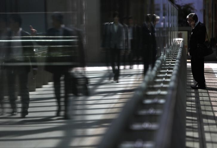 A man uses a mobile phone as pedestrians are reflected in a glass window of a walkway in Tokyo's business district September 30, 2013. Japan's jobless rate unexpectedly rose slightly in August, but the availability of jobs hit the highest level in more than five years, government data showed on Tuesday, in an encouraging signal for its efforts to end deflation. Picture taken September 30, 2013. REUTERS/Yuya Shino (JAPAN - Tags: BUSINESS EMPLOYMENT POLITICS)