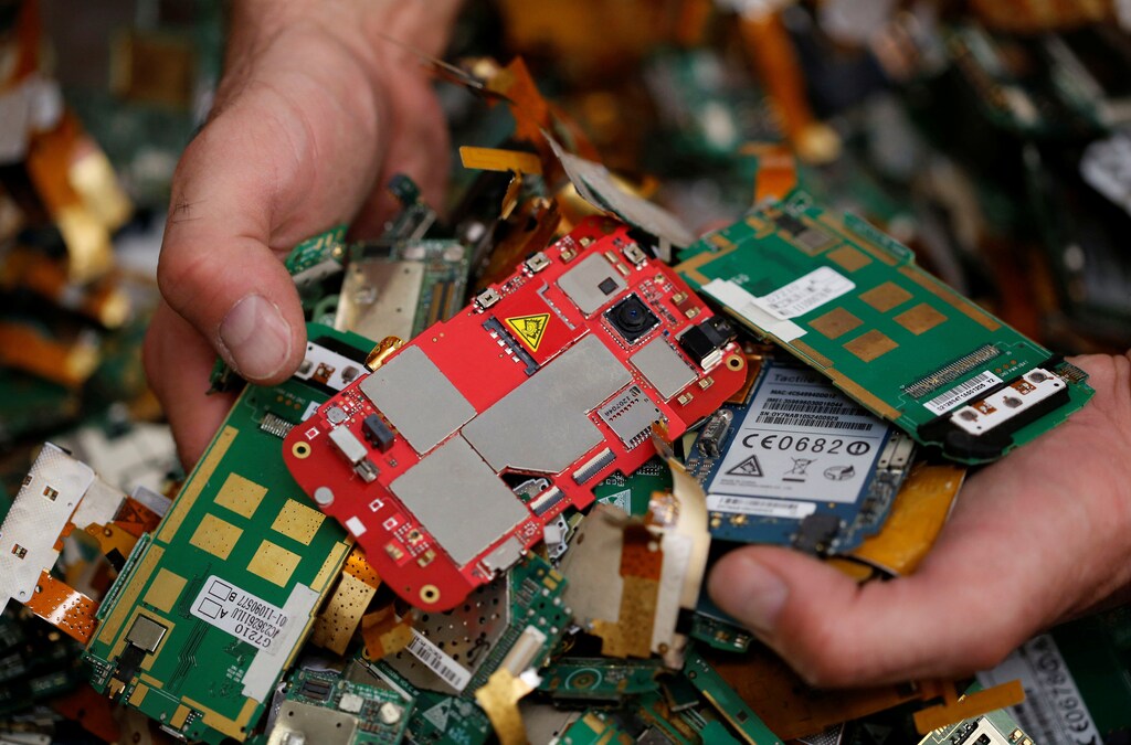 A recycling company worker selects computer cards of old cell phones
