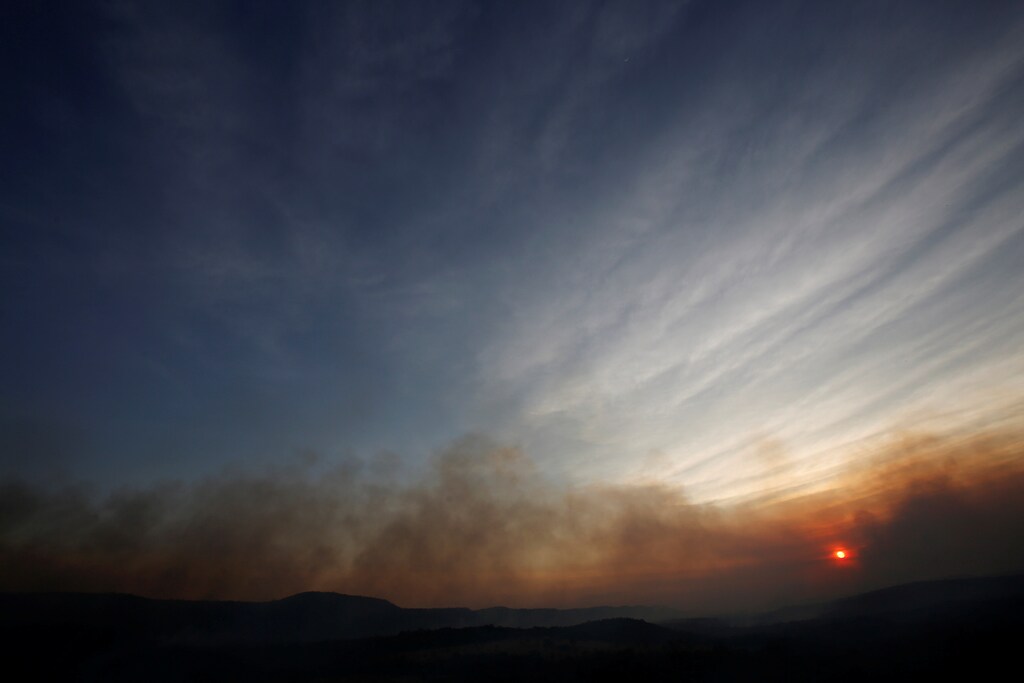 Smoke from a forest fire is seen during sunset in an area of Chapada dos Veadeiros National Park, in Alto Paraiso, Goias, Brazil, October 24, 2017. REUTERS/Ueslei Marcelino - RC18F8C41200