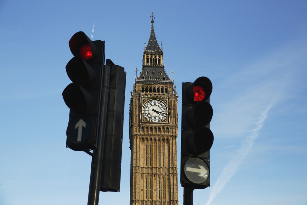 Red traffic lights stop traffic in front of the Big Ben bell tower at the Houses of Parliament in London