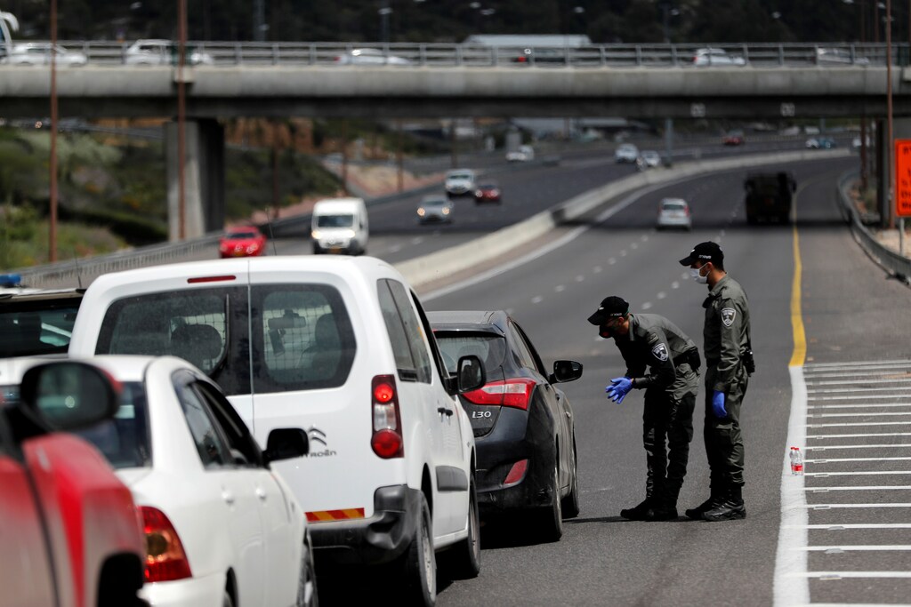Border policemen chat to a driver at a roadblock set-up by police as they begin to enforce a national lockdown to fight the spread of the coronavirus disease (COVID-19) on a road leading to Jerusalem, near Ein Hemed, Israel April 7, 2020. REUTERS/Ronen Zvulun - RC2MZF9ZZ2OD