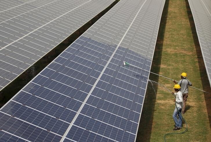 Workers clean photovoltaic panels inside a solar power plant in Gujarat, India, in this July 2, 2015 file photo. The likely collapse of SunEdison Inc's solar project in India, the first of 32 planned "ultra mega" complexes, could delay Prime Minister Narendra Modi's goal to increase renewable energy fivefold by several years and probably cost consumers more. REUTERS/Amit Dave/Files
