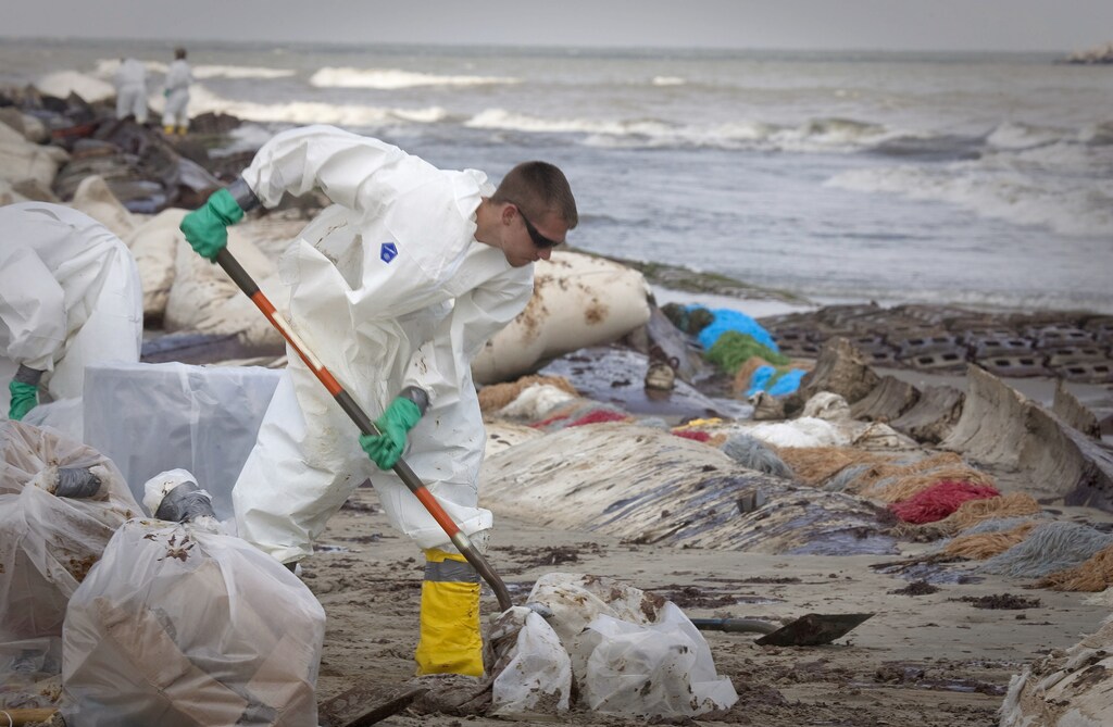 A worker contracted by British Petroleum scrapes oil from a beach after it was inundated by the oil spill from the Deepwater Horizon spill in Port Fourchon, Louisiana May 23, 2010. REUTERS/Lee Celano (UNITED STATES - Tags: DISASTER BUSINESS ENERGY) - GM1E65O0FYX01