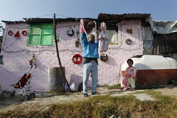 A man hangs up clothes to dry in a low-income neighborhood in Mexico City December 8, 2011. When President Felipe Calderon came to power five years ago, he pledged to cut rampant poverty in Mexico. Instead, millions more have joined the ranks of the poor and half of Mexico's population lives below the poverty line. Picture taken December 8, 2011. To match MEXICO-POVERTY/ REUTERS/Edgard Garrido (MEXICO - Tags: POLITICS SOCIETY POVERTY)