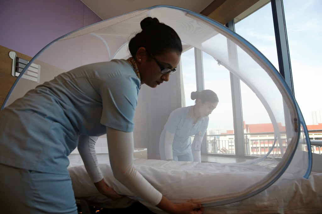 Nurses set up a mosquito tent over a hospital bed in Singapore.