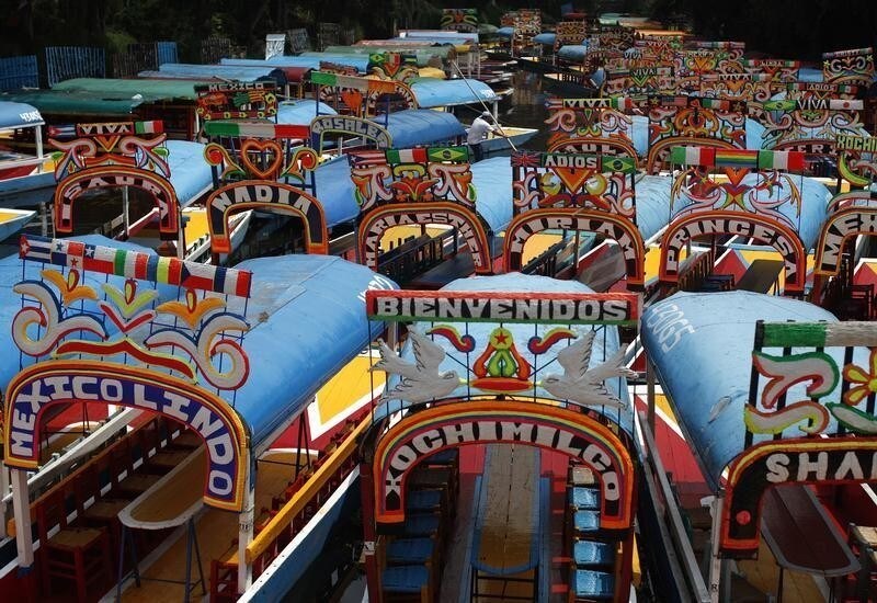 Trajineras (boats) are seen parked at one of the canals of Xochimilco in Mexico City July 17, 2012. The trajineras are colorful, flower adorned wooden boats use as tourist attraction to visit the Chinampas or 'floating gardens' in the ancient canals of this city. Xochimilco means "the place of flowers" in Nahuatl, one of the languages spoken by the Aztecs before the Spanish conquest. REUTERS/Tomas Bravo (MEXICO - Tags: SOCIETY TPX IMAGES OF THE DAY TRAVEL) - RTR350XQ