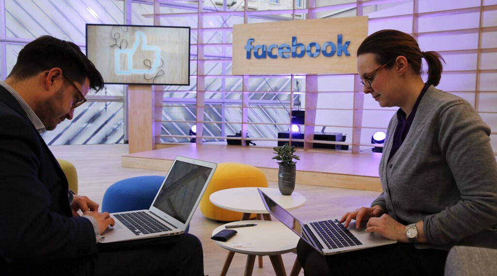 People work with their laptops in front of the Facebook logo at the new Facebook Innovation Hub during a preview media tour in Berlin, Germany, February 24, 2016.