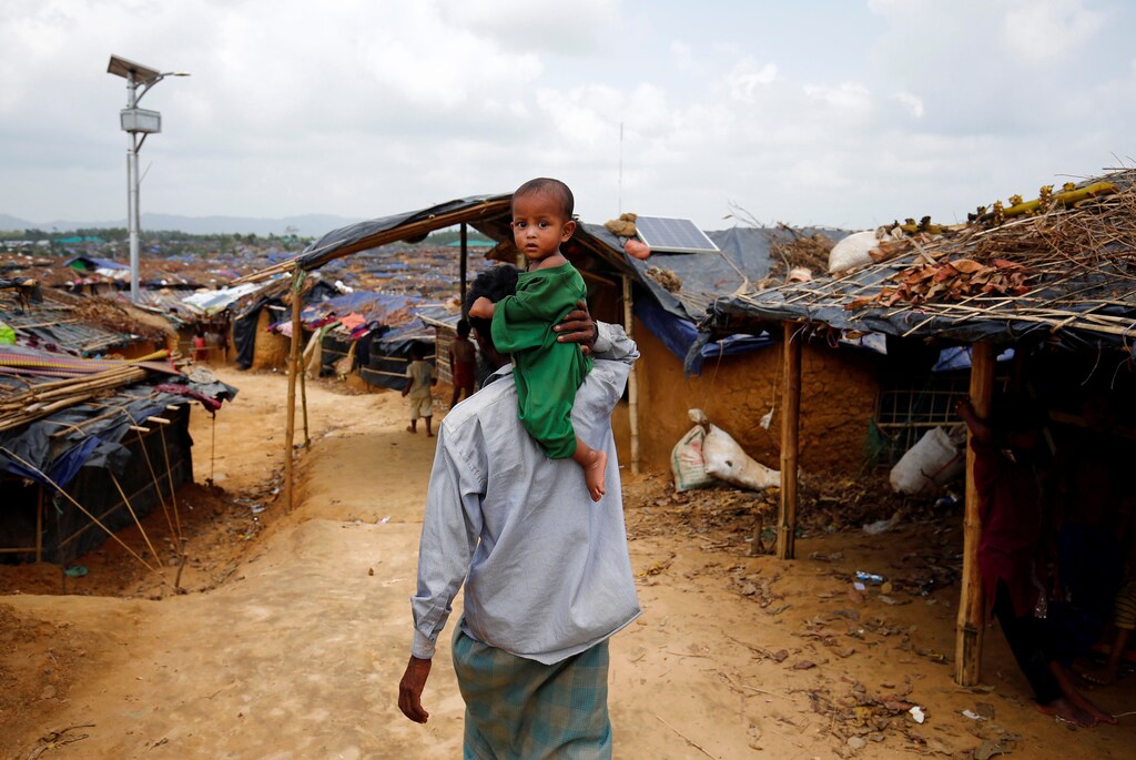 A Rohingya refugee man walks on as he carries a child on his shoulder at the Kutupalang Makeshift Refugee Camp in Cox's Bazar, Bangladesh, June 1, 2017. REUTERS/Mohammad Ponir Hossain - RTX38IMU
