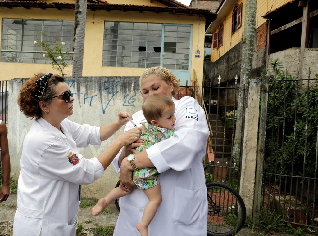 A health agent vaccinates a child on the street in a neighbourhood where the risk of infection is high, during an emergency campaign of vaccination against yellow fever in Sao Paulo.