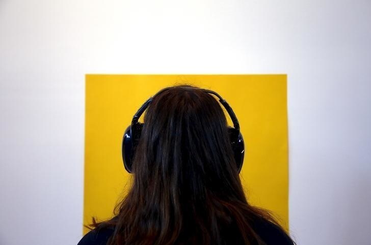 A visitor wearing noise-cancelling headphones looks at a yellow piece of paper stuck to a wall as she tours the latest project by performance artist Marina Abramovic titled "Marina Abramovic: In Residence" on display as part of a public art project in Sydney, Australia June 23, 2015. The project involves visitors being a part of the artwork, making them perform exercises, complete tasks and resting while wearing noise-cancelling headphones. REUTERS/David Gray ATTENTION EDITORS - FOR EDITORIAL USE ONLY. NOT FOR SALE FOR MARKETING OR ADVERTISING CAMPAIGNS.