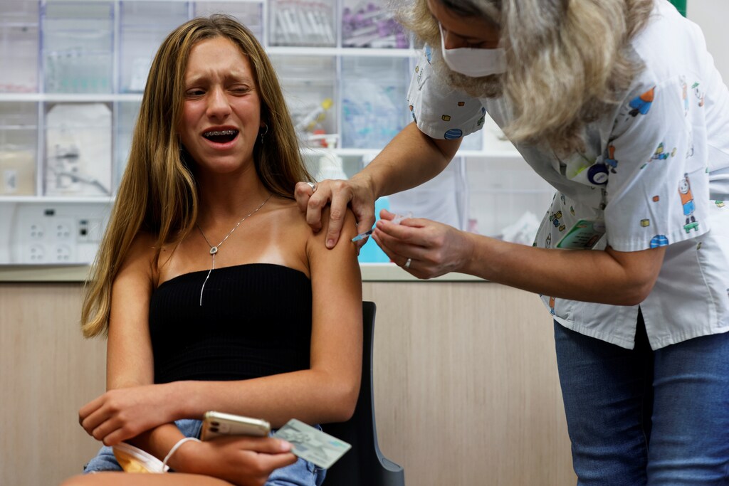 A teenager reacts while receiving a dose of a vaccine.