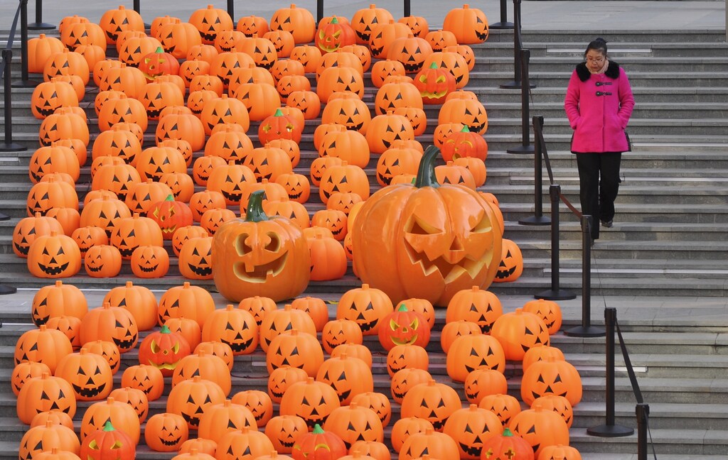 A woman walks down a stairway partially filled with decorations in the shape of carved pumpkins to celebrate Halloween in Shenyang, Liaoning province, China, October 30, 2015. Picture taken October 30, 2015. REUTERS/Stringer CHINA OUT. NO COMMERCIAL OR EDITORIAL SALES IN CHINA TPX IMAGES OF THE DAY - GF20000039852