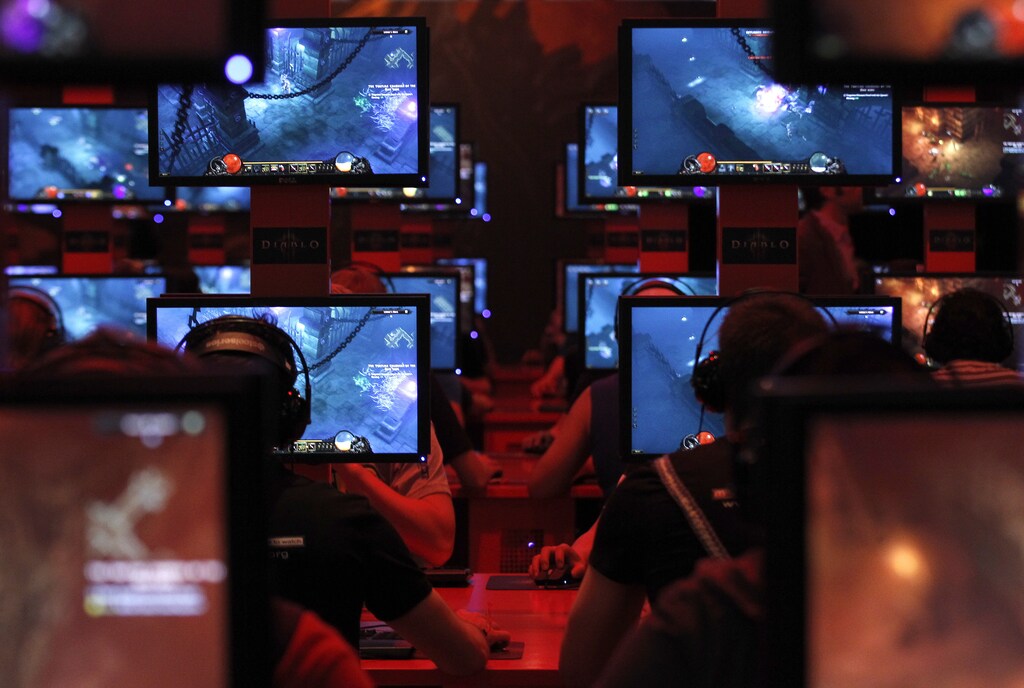 Visitors play ''Diablo'' at the Blizzard exhibition stand during the Gamescom 2011 fair in Cologne August 18, 2011. The Gamescom convention, Europe's largest video games trade fair, runs from August 17 to August 21. REUTERS/Ina Fassbender (GERMANY - Tags: SOCIETY BUSINESS IMAGES OF THE DAY) - BM2E78I16H901