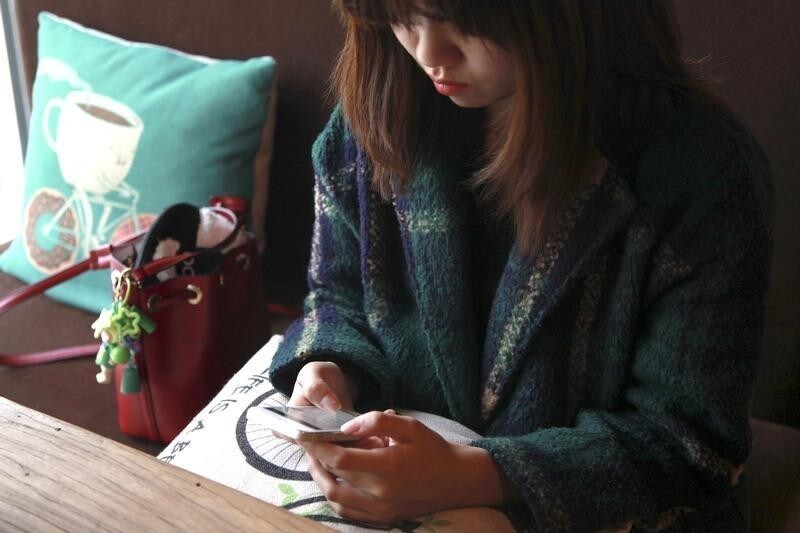 A woman uses an app on a mobile phone at a cafe in Beijing, China, April 11, 2016. REUTERS/Shirley Feng/File Photo - D1AETFCJTHAA