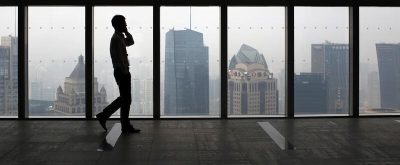 A man talks on a mobile phone as he walks past the view of the Shanghai skyline, September 4, 2014. Companies facing antitrust probes in China are subject to a host of pressure tactics from regulators, a business lobby said, in the latest report to cite due process concerns over China's anti-monopoly enforcement. REUTERS/Carlos Barria (CHINA - Tags: BUSINESS POLITICS CITYSCAPE) - GM1EA9416MF01