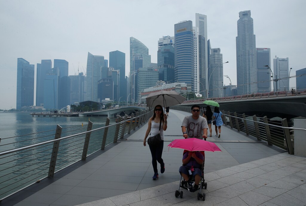 People pass skyline of Singapore's central business district shrouded by haze August 26, 2016. REUTERS/Edgar Su - RTX2N4BX