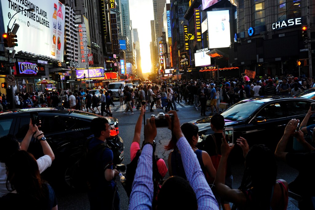 People take pictures as the sun sets over Manhattan aligned exactly with the streets in a phenomenon known as "Manhattanhenge", in New York City, U.S., July 11, 2016. REUTERS/Mark Kauzlarich - RTSHGZ2